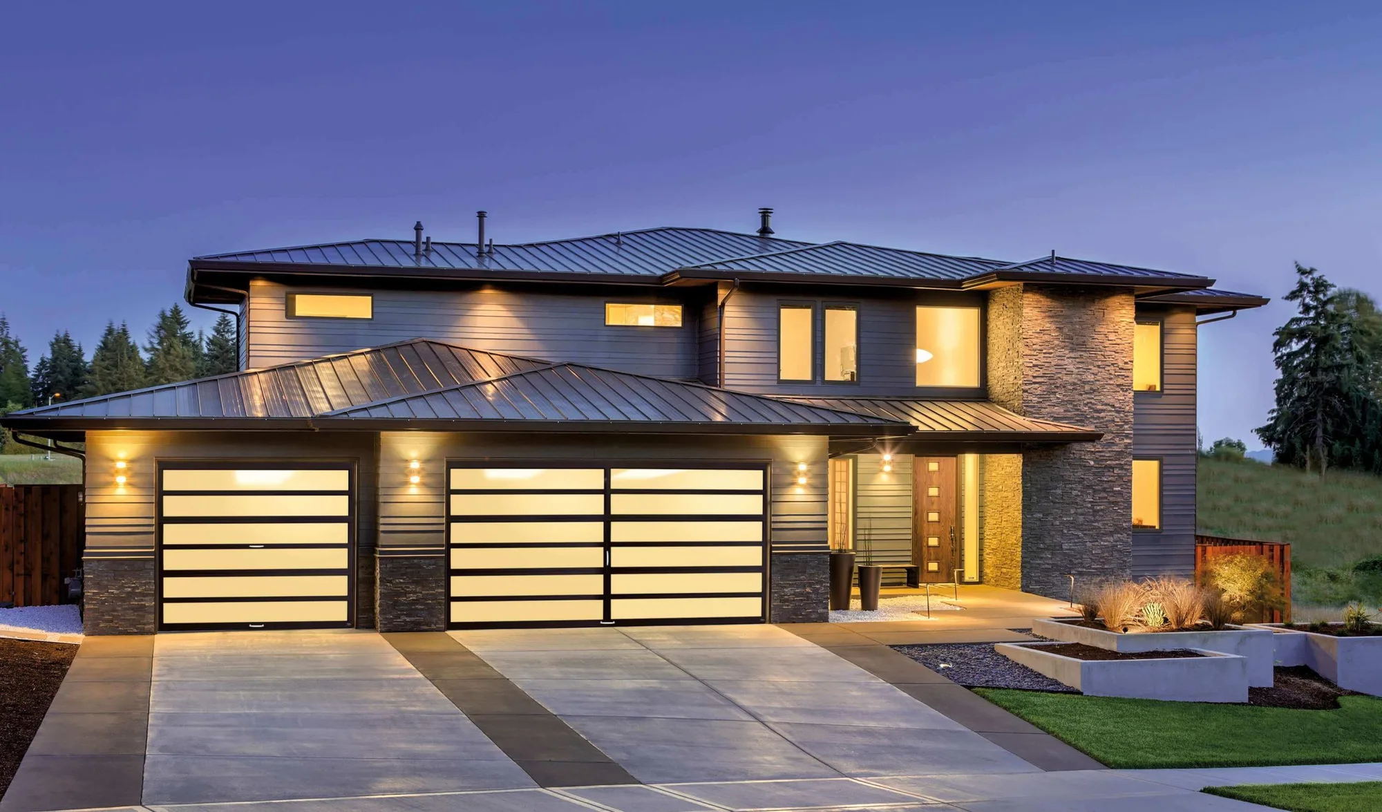 Full-view glass garage doors on a modern home at dusk