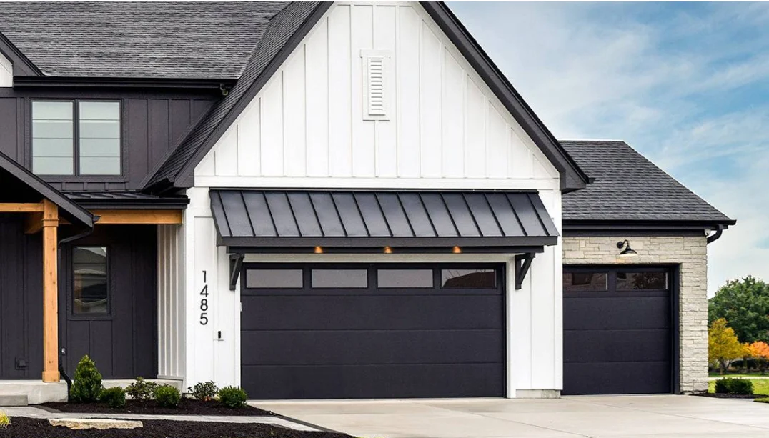Modern farmhouse with black steel garage doors and metal awning
