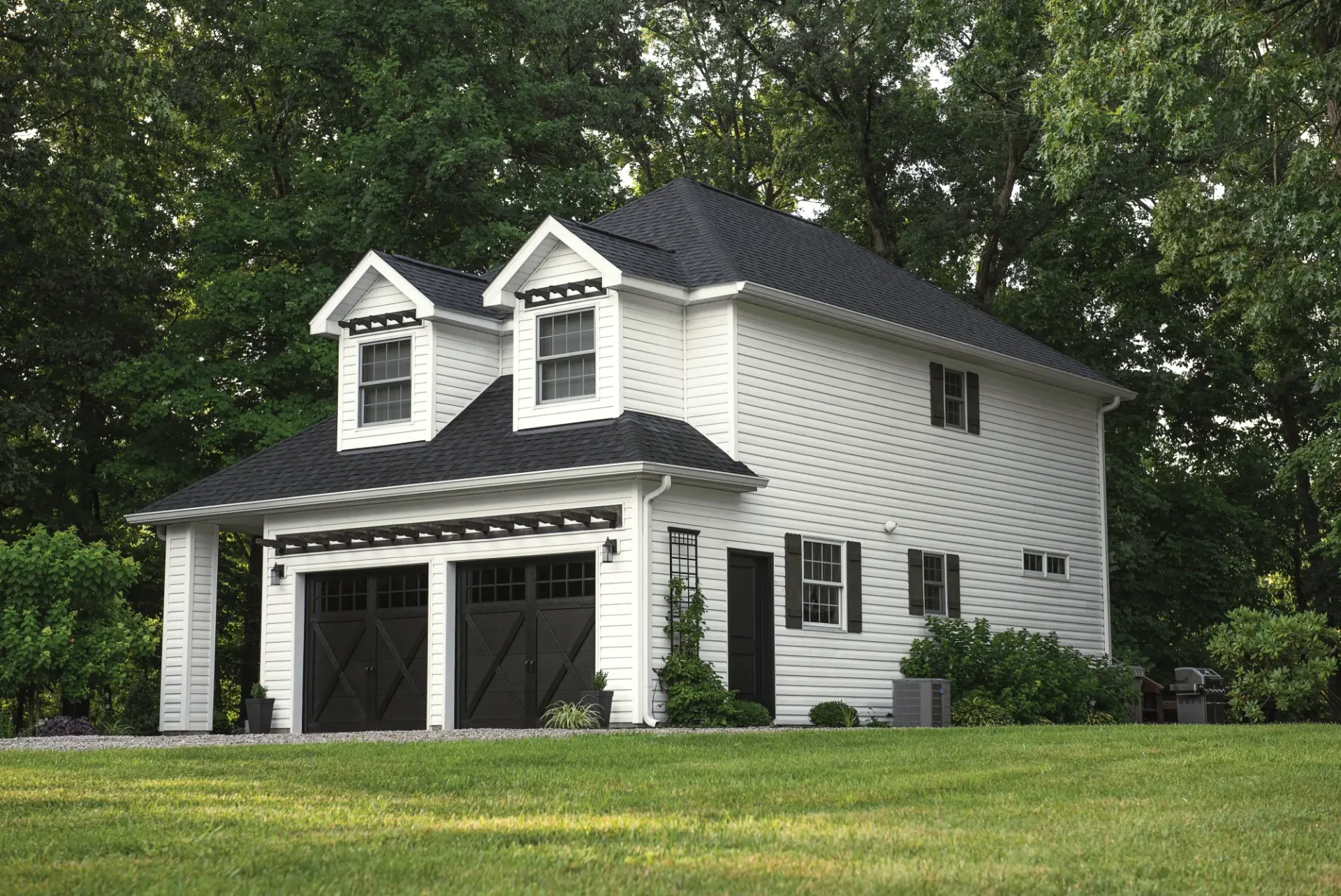 White two-story garage with dark carriage-style garage doors
